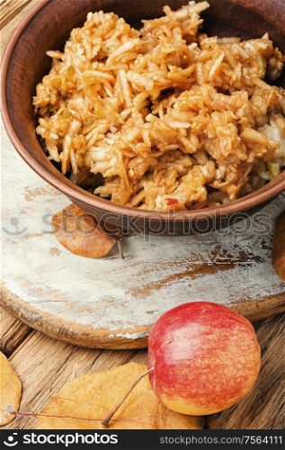 Grated ripe autumn apples in a plate on a wooden old table. Grated ripe apples
