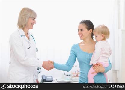 Grateful mom shaking hand to middle age pediatric doctor