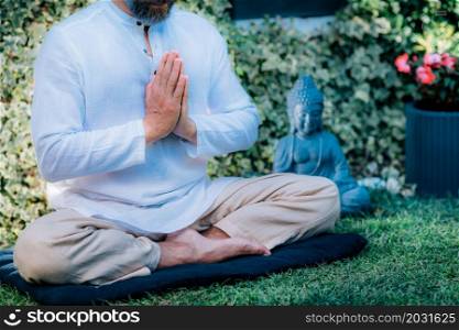 Gratefulness meditation. Peaceful man sitting in a lotus pose and meditating, keeping hands together in a prayer position. . Gratefulness Meditation.