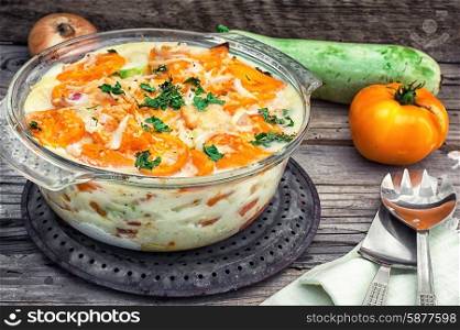 gratin of zucchini and yellow tomatoes on wooden background
