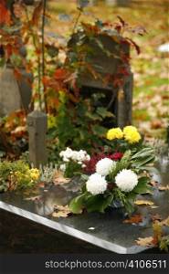 Grave With Flowers And Autumn Leaves