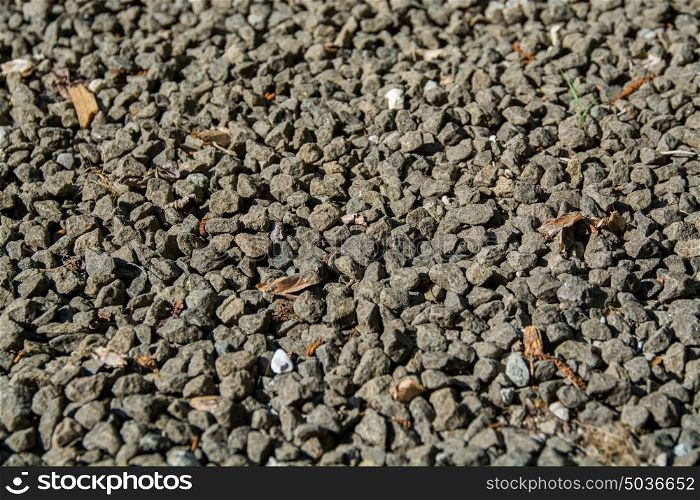 gravel background, grey gravel rocks and some brown old leaves