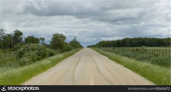 Gravel road passing through prairie landscape, Manitoba, Canada