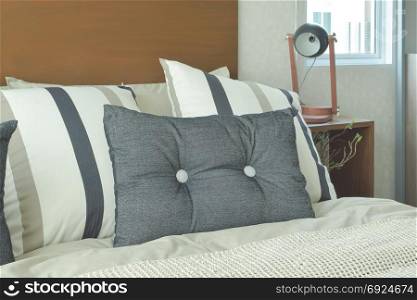 Gray and brown strip pillows setting on bed with brown headboard
