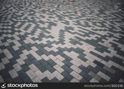 Gray and white patterned paving tiles on the ground of street, perspective view. Cement brick squared stone floor background. Concrete paving slab flagstone. Sidewalk pavement pattern.