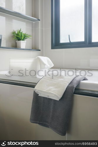 Gray and white towel and bathtub in modern interior bathroom