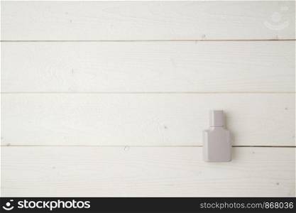 gray bottle of perfume on a light wooden background. flat lay