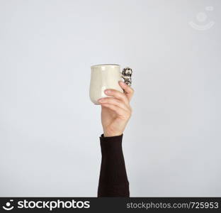 gray ceramic cup in female hand on a white background, hand raised up, copy space