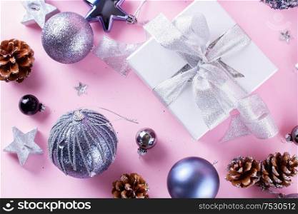 Gray Christmas decorations with gift box on pink background, top view. Gray Christmas decorations on pink