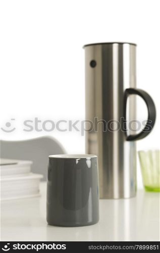 Gray Coffee Cup Beside Silver Vacuum Flask. Close up Single Gray Coffee Cup Beside Silver Vacuum Flask on Top of the Table with White Background.