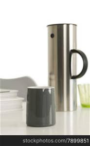 Gray Coffee Cup Beside Silver Vacuum Flask. Close up Single Gray Coffee Cup Beside Silver Vacuum Flask on Top of the Table with White Background.