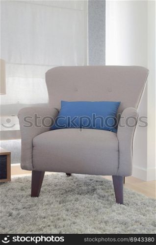 Gray color retro style armchair with blue pillow in living room