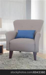 Gray color retro style armchair with blue pillow in living room