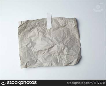 gray crumpled sheet of paper glued with white adhesive tape on a white background, place for text