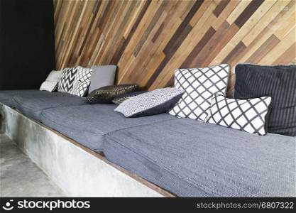 gray cushion and pillow with skew wooden wall