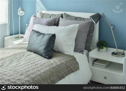 Gray, dark gray and beige pillows on bed with blue wall bedroom