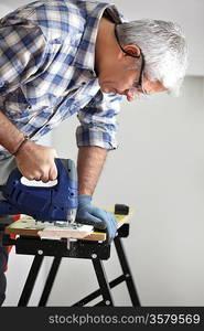 Gray-haired handyman using an electric drill