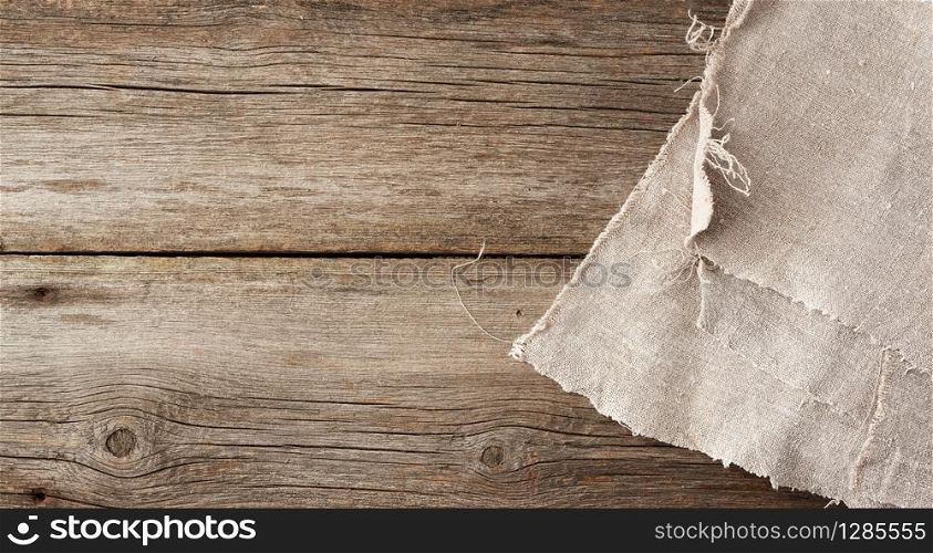 gray kitchen textile towel folded on a gray wooden table from old boards, top view, empty space. Rustic texture. Retro background