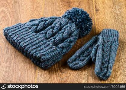 gray knitting cap and mittens on wooden background