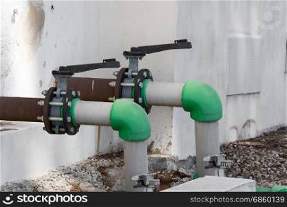Gray old valve and old green water pipe. Industrial water valve or control valve.