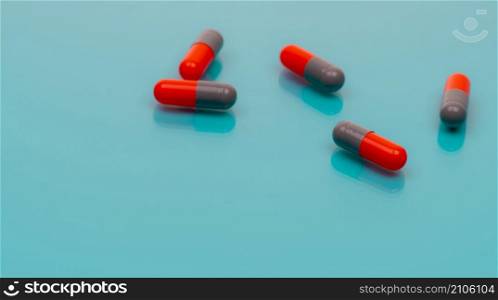Gray-orange antibiotic capsules pill spread on blue background. Pharmacy banner. Prescription drug. Antibiotic drug resistance. Pharmaceutical industry. Healthcare and medicine. Antimicrobial drugs.