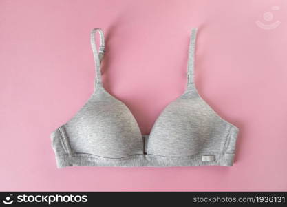 Gray organic or recycled cotton bra on pastel pink background, top view, copy space, flat lay. Concept of femininity, comfort, home clothes, underwear, natural textile, minimal style. Horizontal.