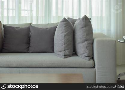 Gray pillows on beige color sofa with sheer in background
