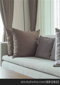 Gray pillows on couch with gray drape in background