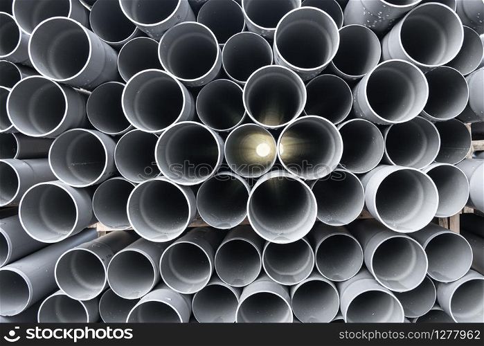Gray PVC tubes plastic pipes stacked in rows with light shinning through