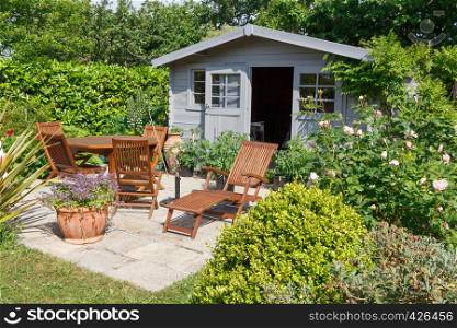 Gray shed with terrace and wooden garden furniture