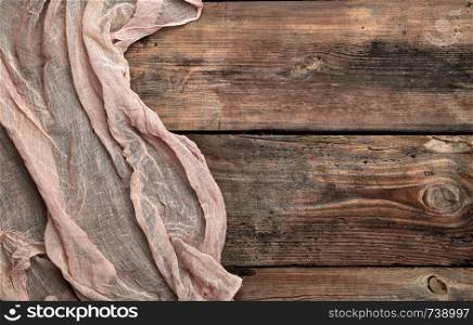 gray textile napkin, brown wooden background, top view, copy space