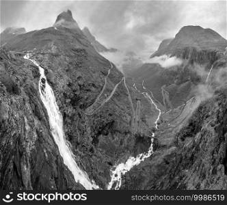 Grayscale. Summer Trollstigen serpentine mountain path road and Stigfossen waterfall view from The Trolls Path Viewpoint, Norway.