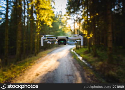 Graz, Austria: 02.01.2020 - Close up shoot of a DJI Quadcopter Drone Mavic mini 249g. Drone flying in sunny forest. DJI is the market leader in drones and aerial photography systems.. Graz, Austria: 02.01.2020 - Close up shoot of a DJI Quadcopter Drone Mavic mini 249g. Drone flying in sunny forest.