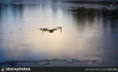 Graz, Austria - December 29 2019. DJI Mavic Mini drone flying in the countryside above frozen lake on sunny winter day. Drone flying.. Graz, Austria - December 29 2019. DJI Mavic Mini drone flying in the countryside above frozen lake on sunny winter day