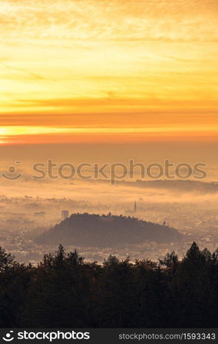 Graz city covered if fog on autumn morning during sunraise. View from Plaubutsch hill surrounding city.. Graz city covered if fog on autumn morning during sunraise.