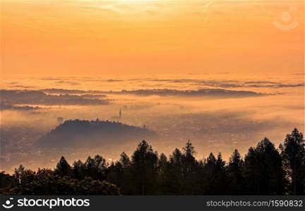 Graz city covered if fog on autumn morning during sunset. View from Plaubutsch hill surrounding city.. Graz city covered if fog on autumn morning during sunset.