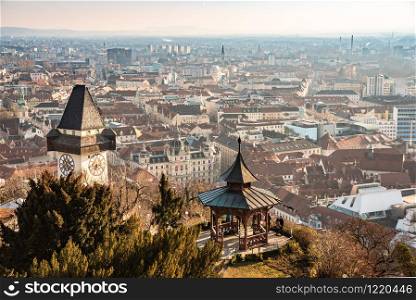 Graz, Styria / Austria - 20.01.2019: View at Graz City from Schlossberg hill, City rooftops, Mur river and city center, clock tower Sun on the winter blue sky. Travel destination.. View of Graz City from castle hill Schlossberg, Travel destination.