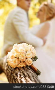 Great bridal bouquet of roses against the background of the bride and groom in the forest . Wedding concept