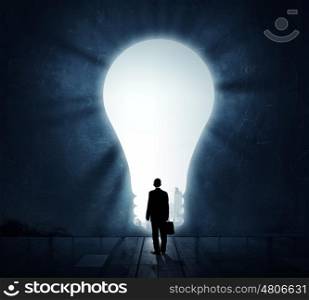 Great bright idea for success. Back view of businessman standing in light of idea concept