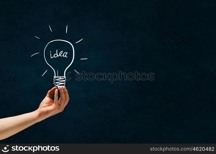 Great bright idea in darkness. Male hand on dark background showing drawn light bulb