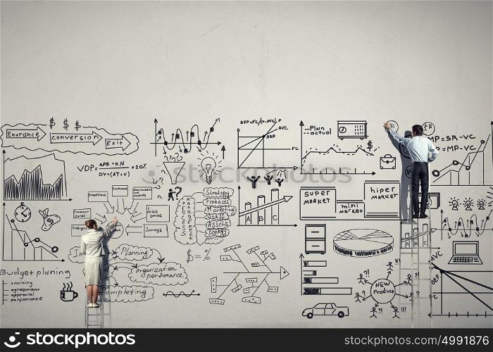 Great business strategy. Back view of businessman and woman standing on ladder and drawing sketch on wall
