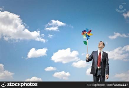 Great day for freedom. Young happy businessman with colorful windmill in hand