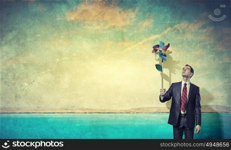 Great day for freedom. Young happy businessman with colorful windmill in hand