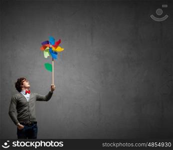 Great day for freedom. Young happy guy in casual with colorful windmill in hand
