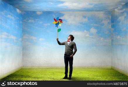 Great day for freedom. Young happy guy in casual with colorful windmill in hand