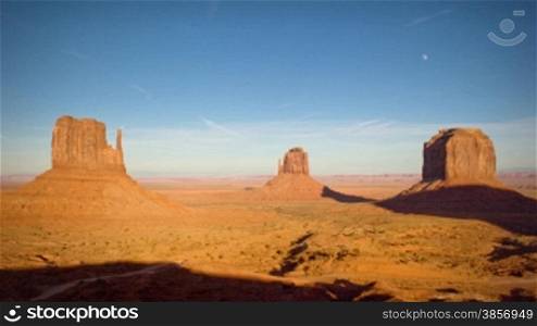 Great for themes of travel, wilderness, adventure, nature, culture, desert, canyon country, destinations, exploration, geology, seasons, time. Full moon rising at sunset over The Mittens formations in Monument Valley.
