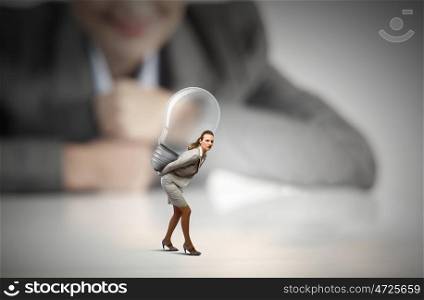 Great idea. Businesswoman carrying big light bulb on back