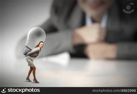 Great idea. Businesswoman carrying big light bulb on back