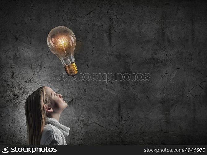 Great idea. Girl of school age looking above at light bulb