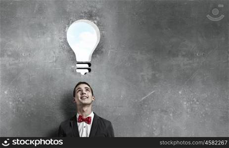 Great idea in his head. Young man in red bowtie looking at idea bulb above head